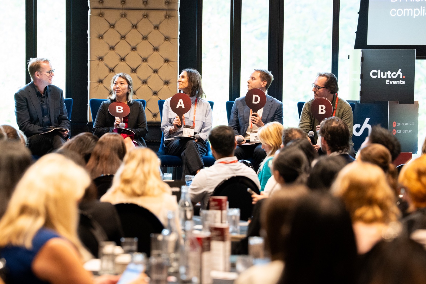A customer experience panel voting with paddles in front of the audience at CustomerTech World