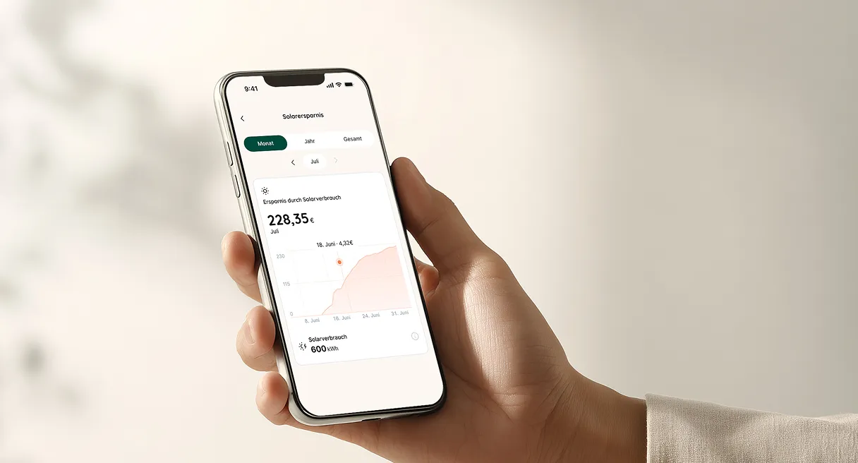 Hand hält ein Smartphone mit einer App, die Solarersparnis für den Monat Juli anzeigt: 228,35 Euro, dazu eine Grafik mit Solarverbrauch von 600 kWh.