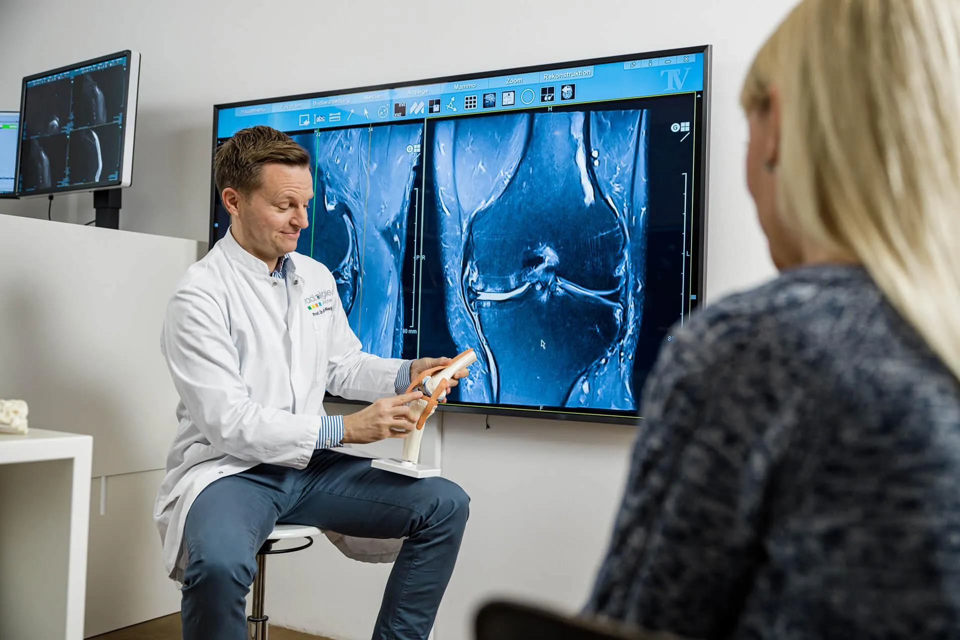 Consultant reviewing knee MRI scans with a patient
