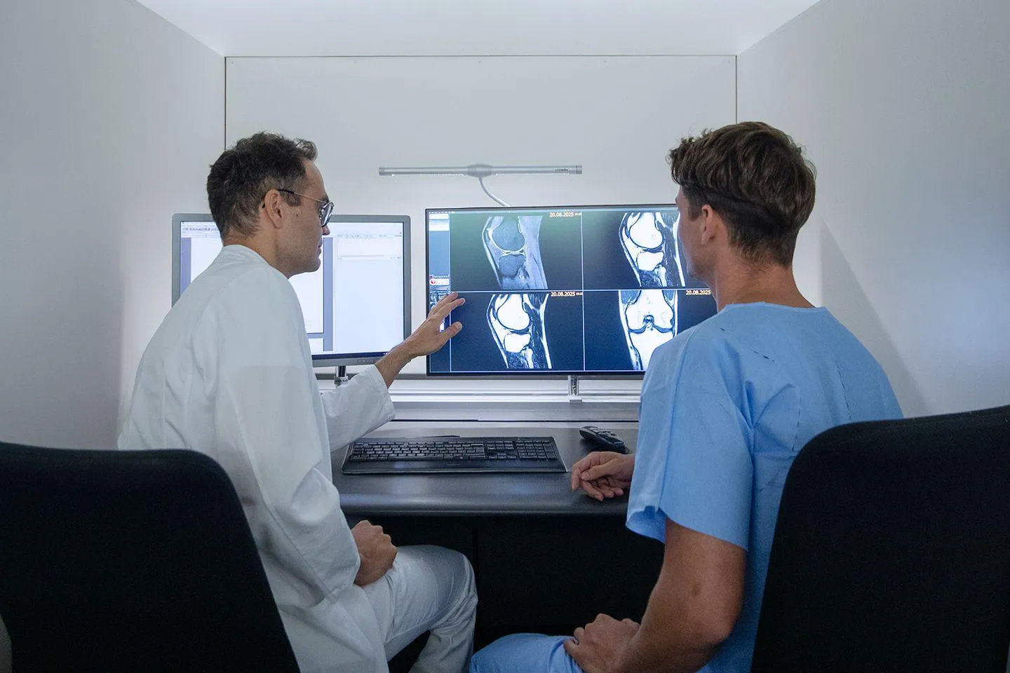 Consultant reviewing knee MRI scans with a patient