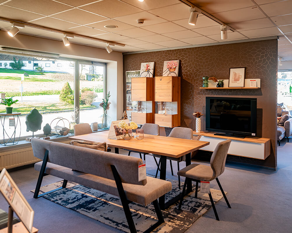 Wohn- und Essbereich mit Wohnwand und Holztisch in der Ausstellung
