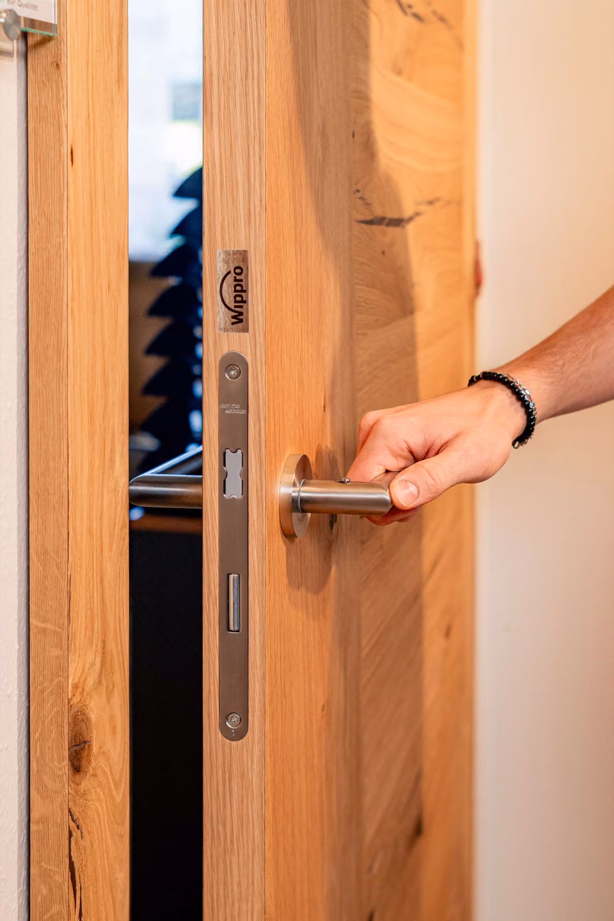 Hand öffnet eine Massivholz-Innentür mit Edelstahlgriff