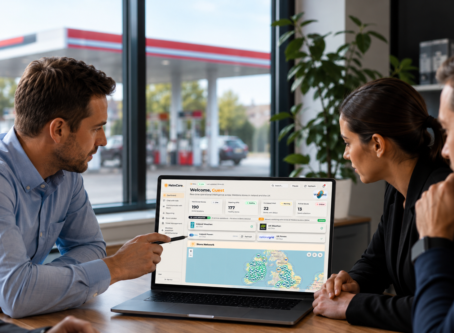 man and woman at a desk overlooking forecourts, on a computer looking at entire retail estate 