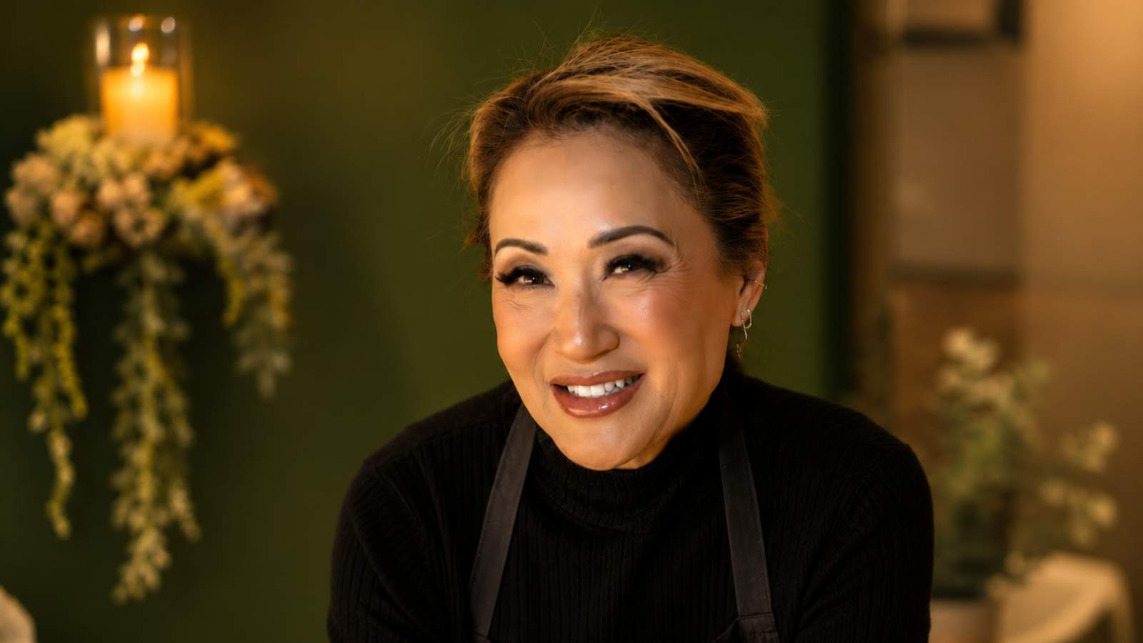 Noreen smiling warmly, a candlelit close-up portrait