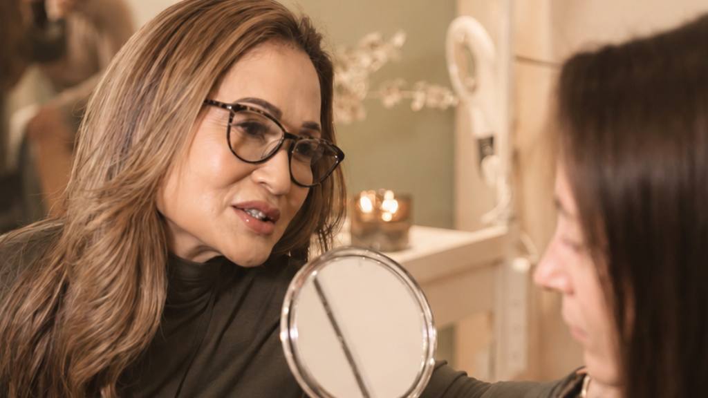 Noreen holding up a mirror for a client during a consultation, tablet in hand