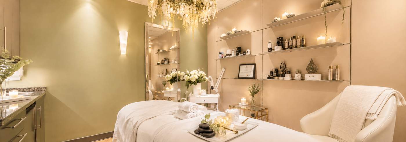 A hanging wisteria and floral installation with warm candlelight below, in a soft neutral treatment room