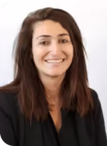 Portrait of a smiling woman with medium-length brown hair wearing a black blazer against a plain white background.