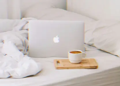 Laptop and a cup of coffee on a bed