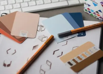 Colour swatches, pens and sketched shapes on a notebook, laid out on a designer's desk