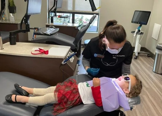 Young sibling in a treatment chair getting a crash course in orthodontics