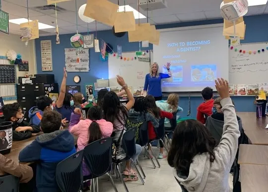Students raising hands during an orthodontics career day presentation