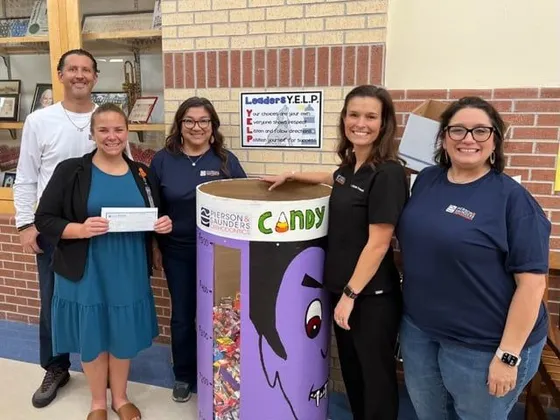 Pierson & Saunders team with a candy buyback donation bin at a local school