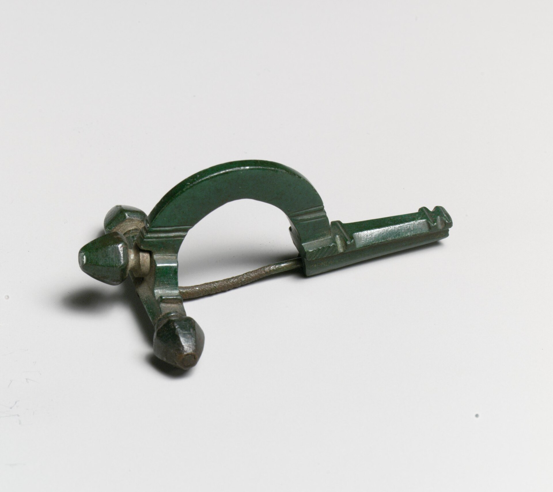 Eine römische Zwiebelknopffibel aus Bronze mit grüner Patina.