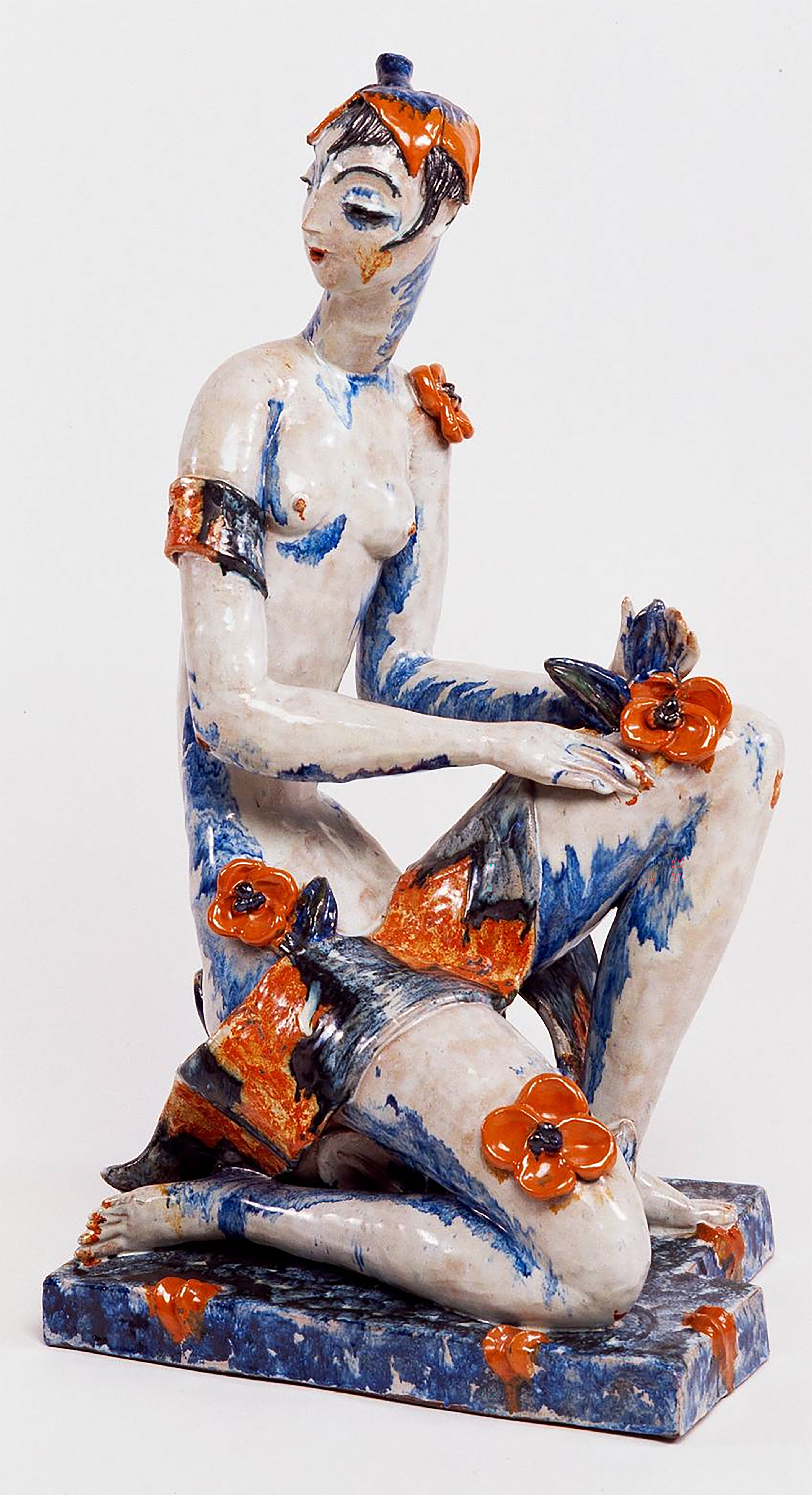 Vally Wieselthiers Keramikfigur „Flora“ von 1928: eine sitzende Frauenfigur aus rotem Scherben, mehrfarbig glasiert, mit aufgesetzten orangen Blüten.