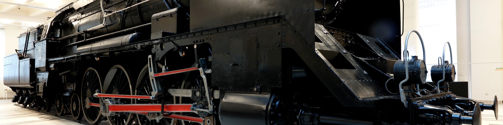 Seitenansicht der schwarzen, restaurierten Dampflokomotive 12.10 der Reihe 214 in der Ausstellung des Technischen Museums Wien.
