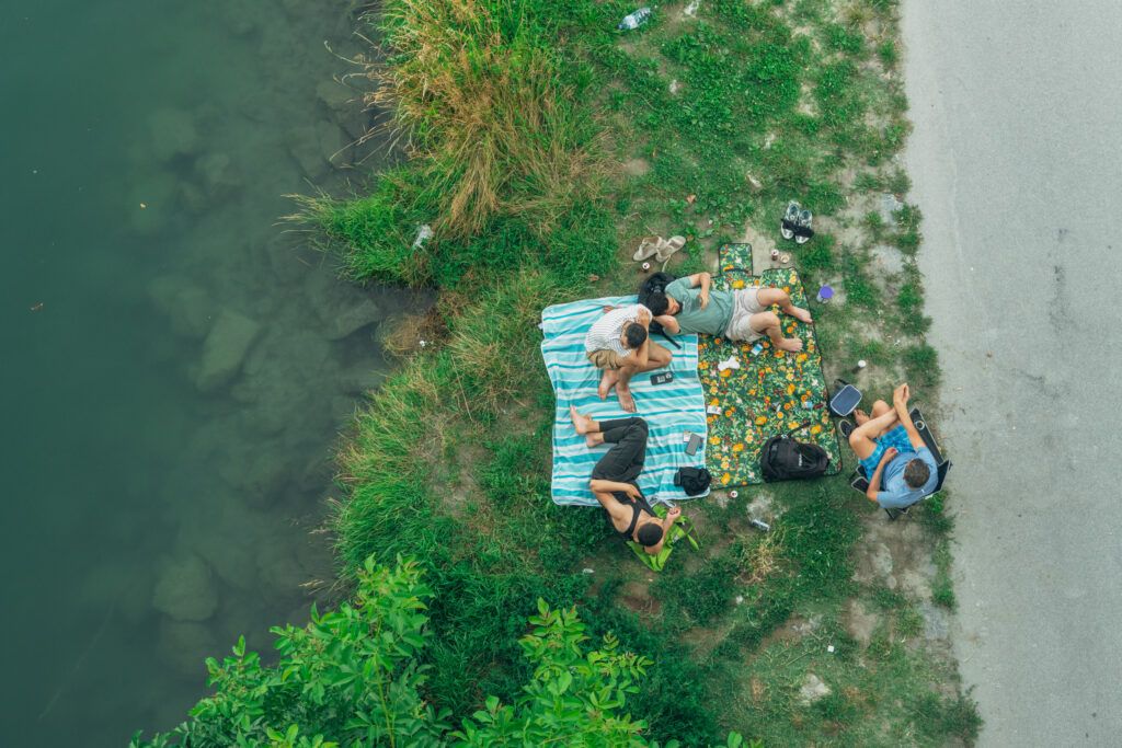 Abendstimmung auf der Donauinsel: Menschen sitzen und stehen am Ufer der Neuen Donau.