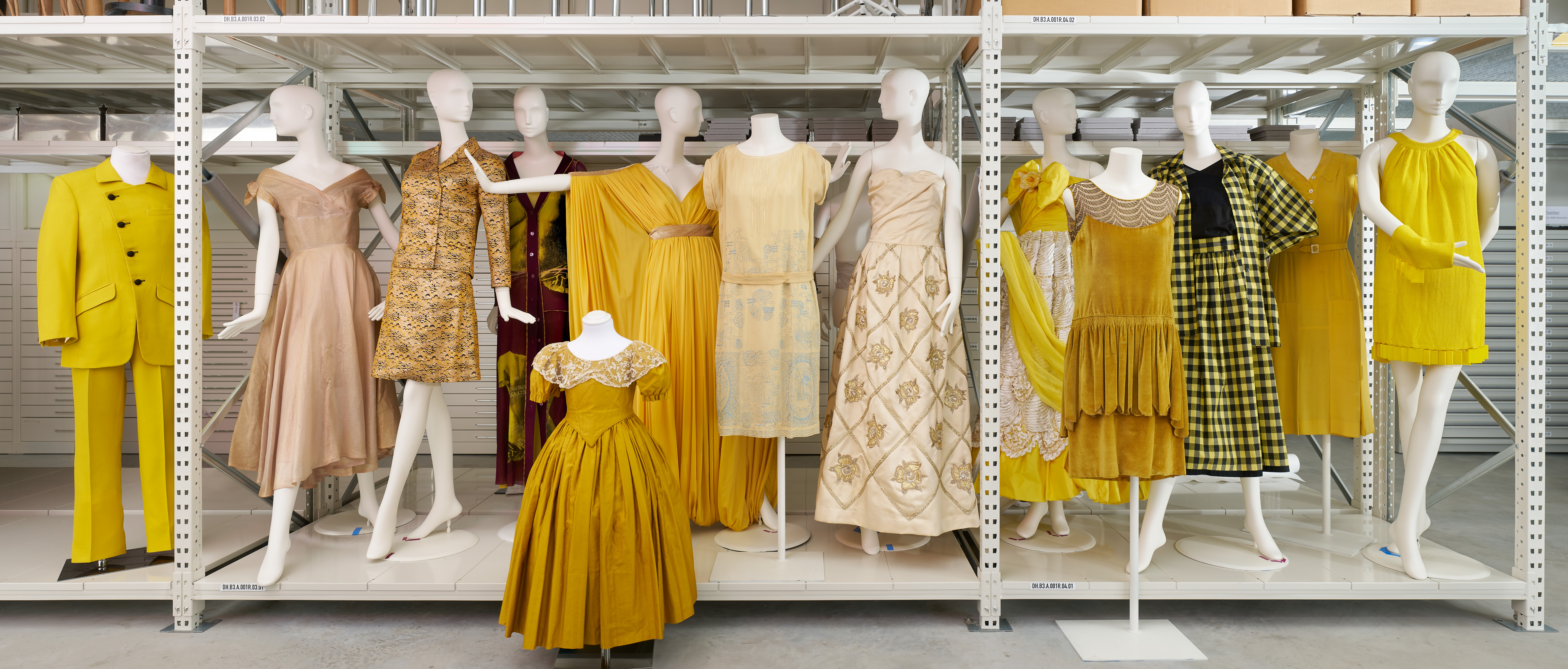 Gelbe und goldfarbene Kleider und ein gelber Herrenanzug auf Figurinen im Depot der Modesammlung des Wien Museums