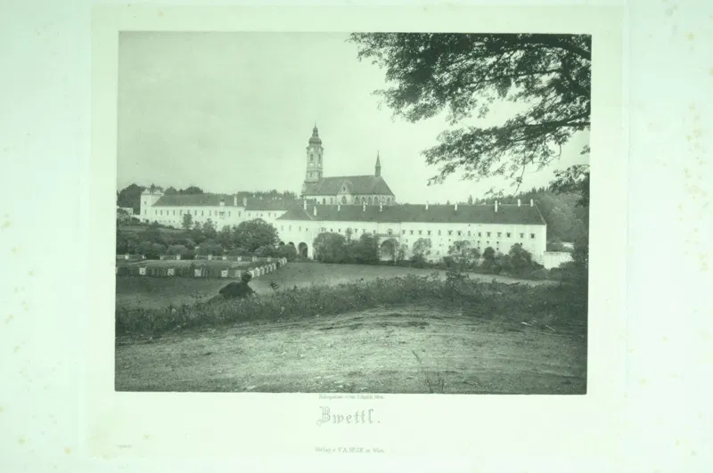 Fotografie vor 1891: Stift Zwettl mit hohem Kirchturm und langen Trakten hinter einer Wiese