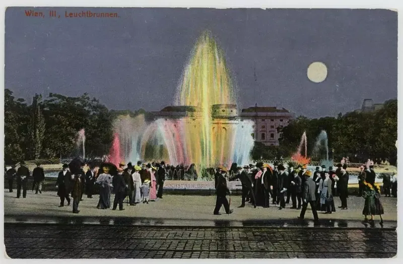 Ansichtskarte 1908: der Hochstrahlbrunnen bei Nacht mit farbig beleuchteten Wasserstrahlen, Vollmond, Spaziergänger, dahinter ein Palais