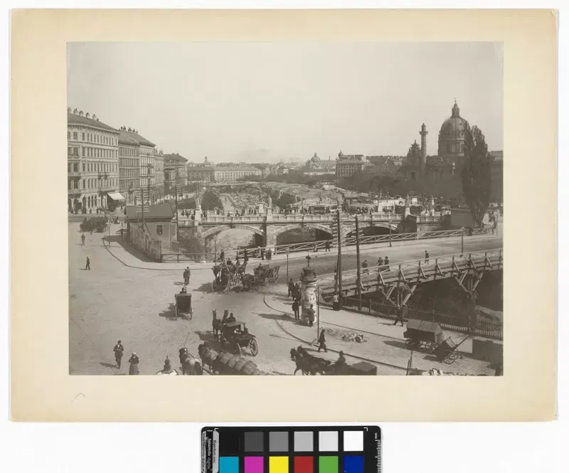 Fotografie 1897: die Elisabethbrücke über den Wienfluss mit einer Notbrücke, Kutschen und Passanten, im Hintergrund die Kuppel der Karlskirche