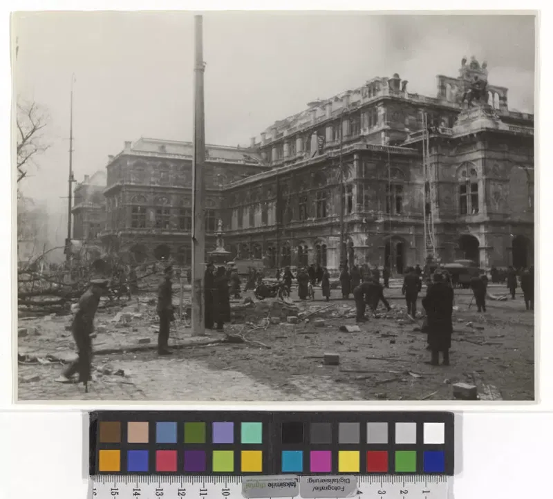 Fotografie 1945: die Wiener Staatsoper nach den Kriegszerstörungen, davor Schutt auf der Straße und Menschen