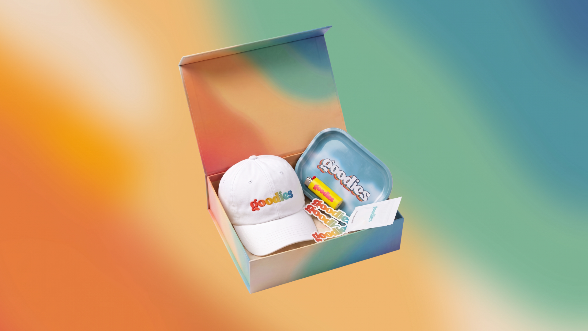 Open Goodies gift box with rainbow-logo hat, rolling tray, lighter and stickers
