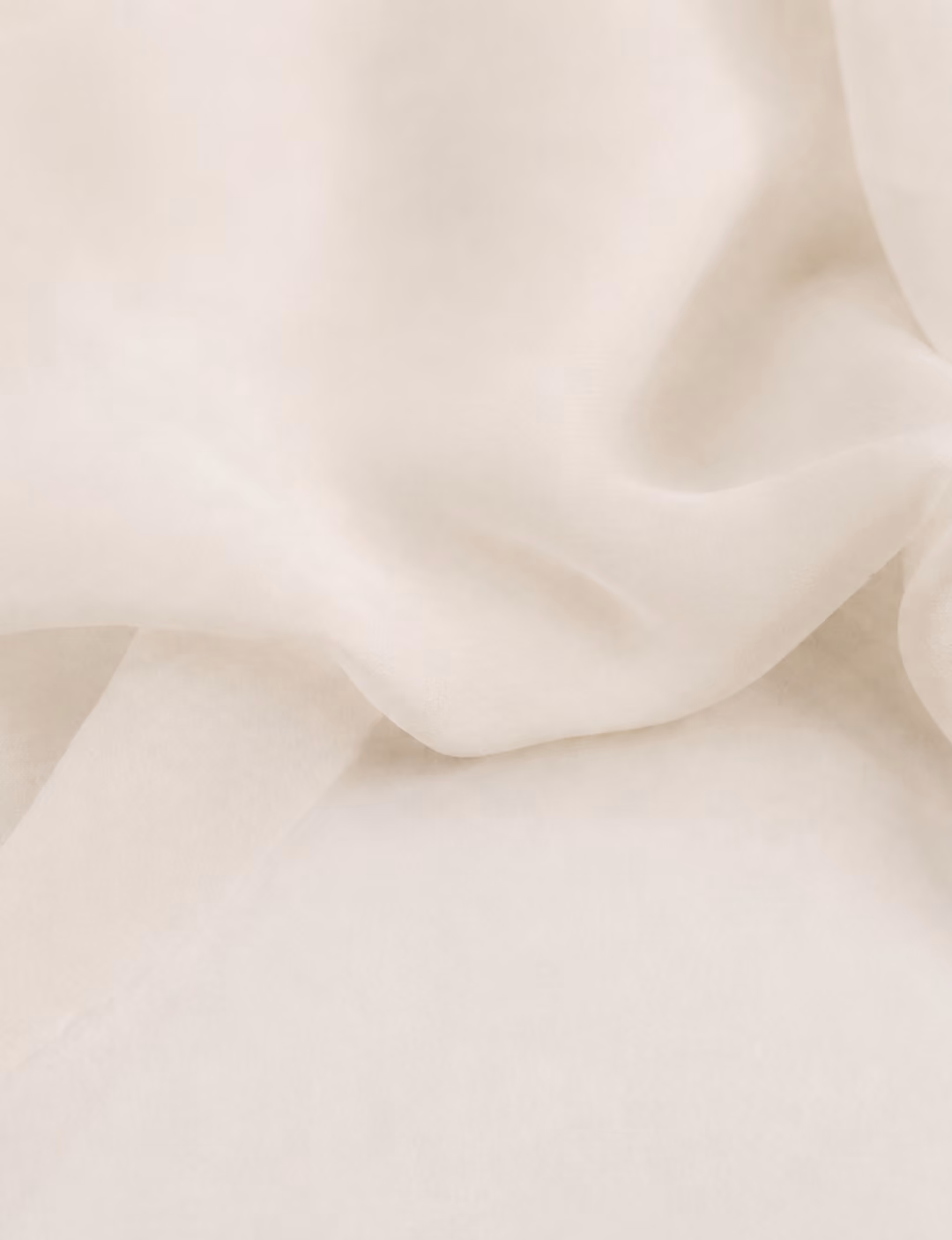 Soft, light beige fabric with gentle folds and a smooth, translucent texture.