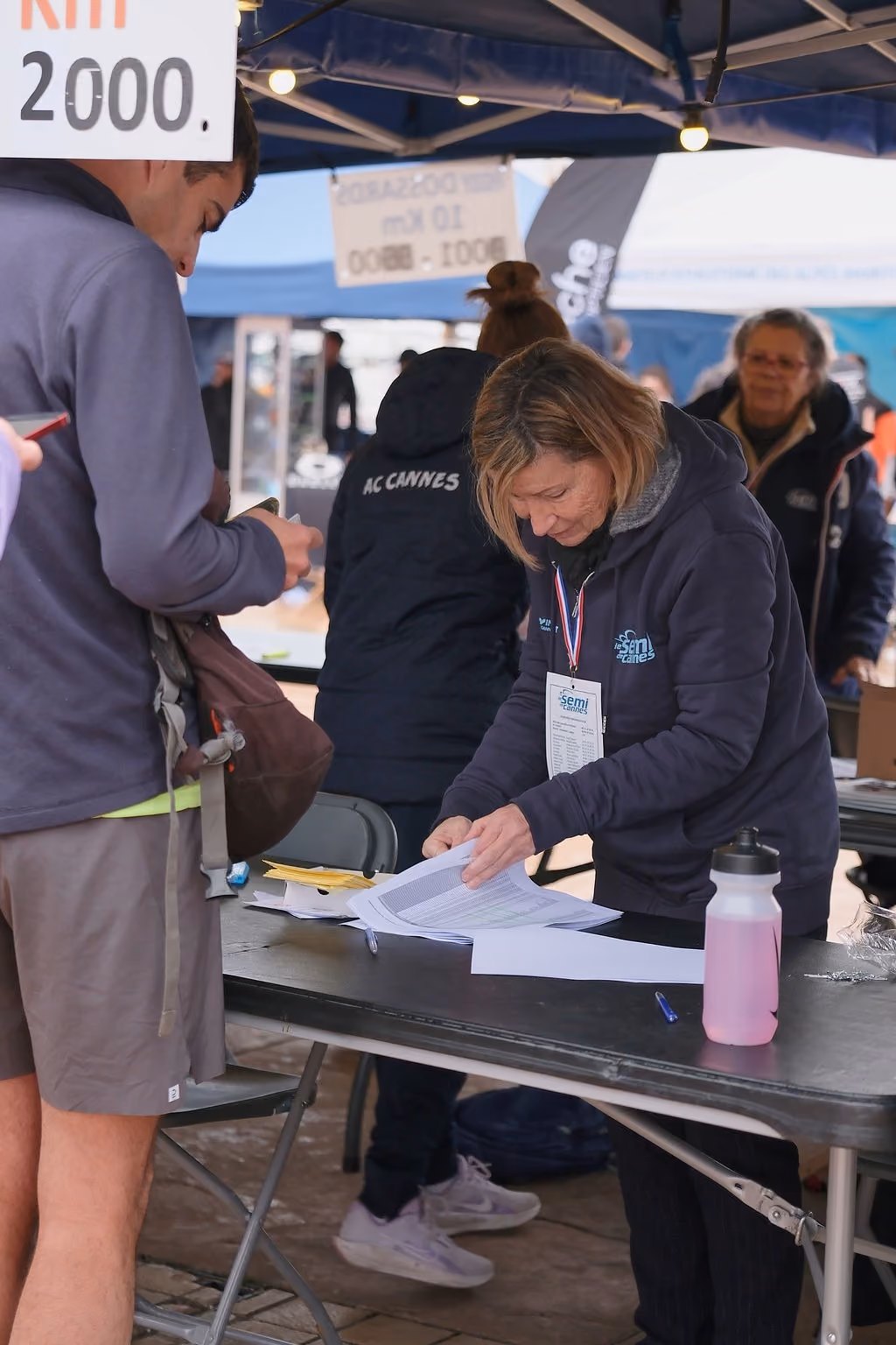 Bénévole vérifiant la liste des inscrits au retrait des dossards