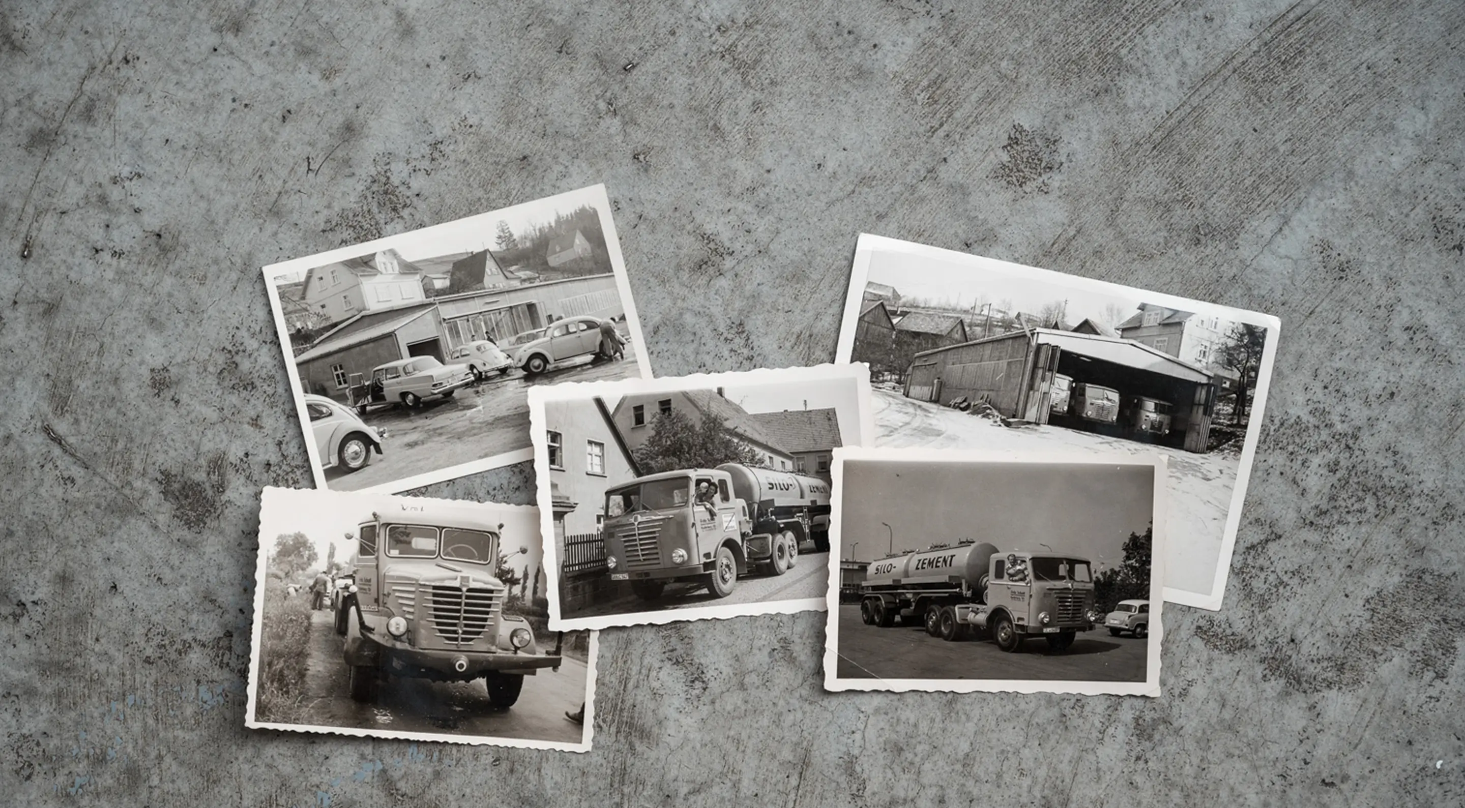 Fünf schwarz-weiße historische Fotos von Lastwagen und Gebäuden der Spedition Schott liegen auf einem grauen Betonuntergrund.