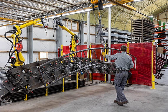 Man manufacturing thundura hoop building metal arch with robots