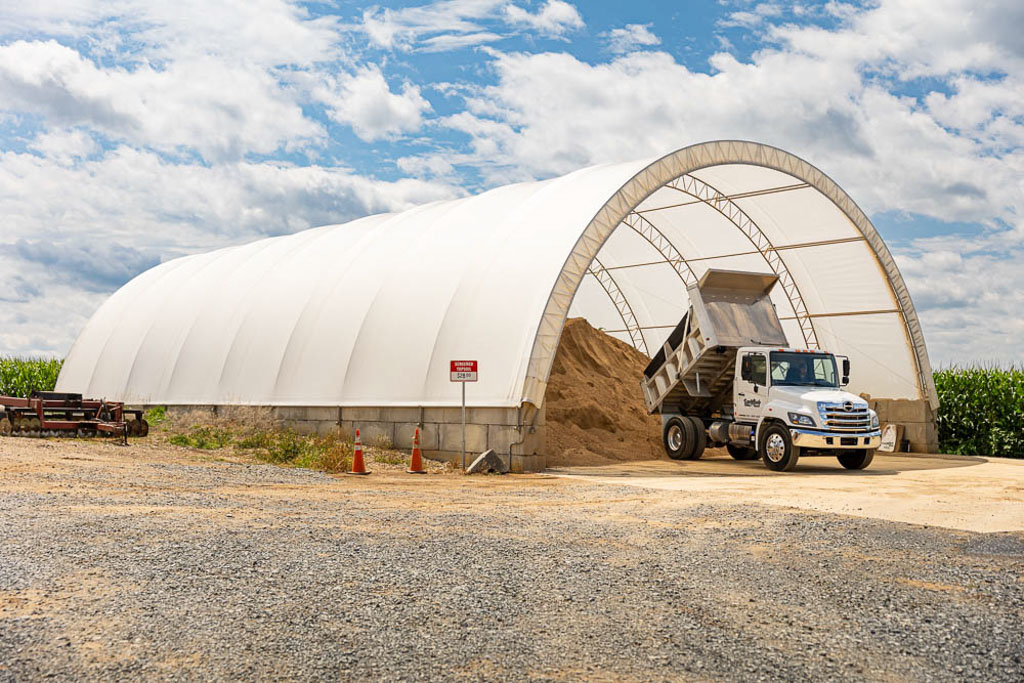 small dump truck dumping shavings in a thundura fabric structure