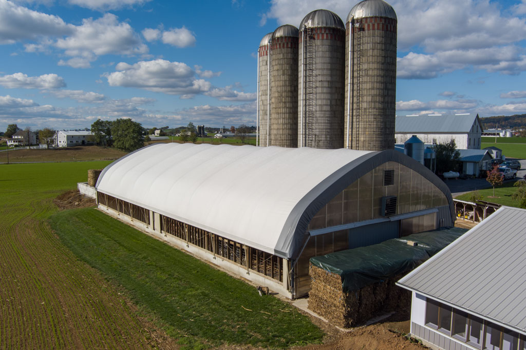 Peaked style thundura fabric structure with several silos in the background