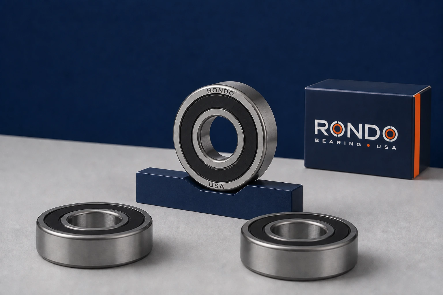 Rondo sealed deep-groove bearing concept with navy packaging, natural steel and a cool-gray studio surface.