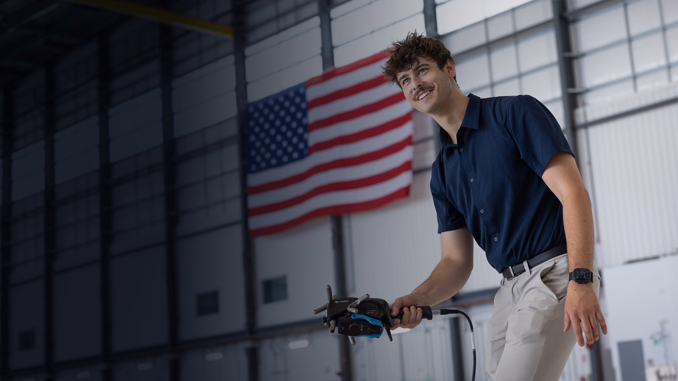 A photo of two people standing on an indoor balcony railing in a large aircraft hangar, dressed in formal business attire, with aviation exhibits and aircraft displays visible in the background.