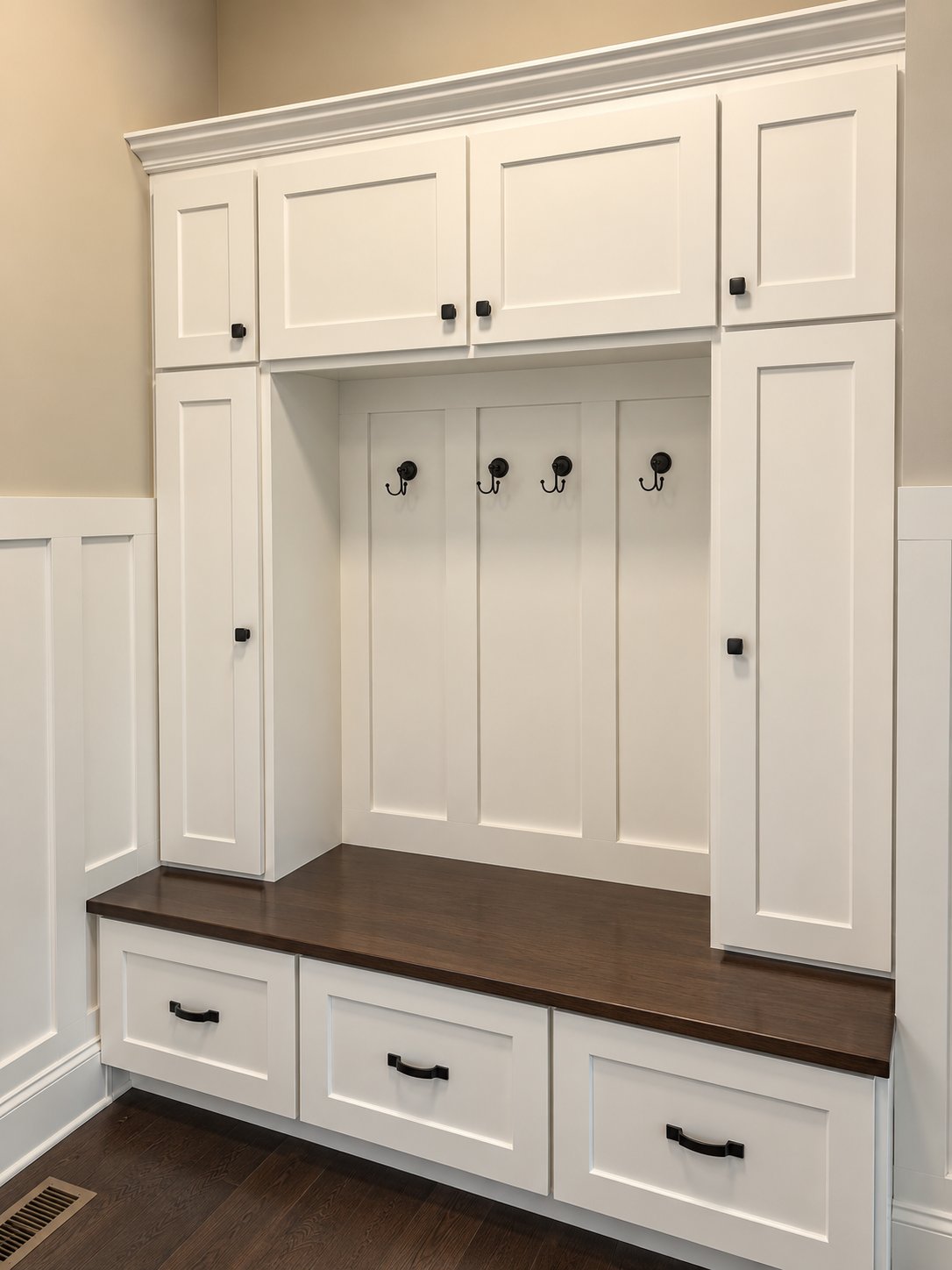 White Shaker mudroom lockers with upper cabinets, coat hooks, storage drawers and a walnut bench