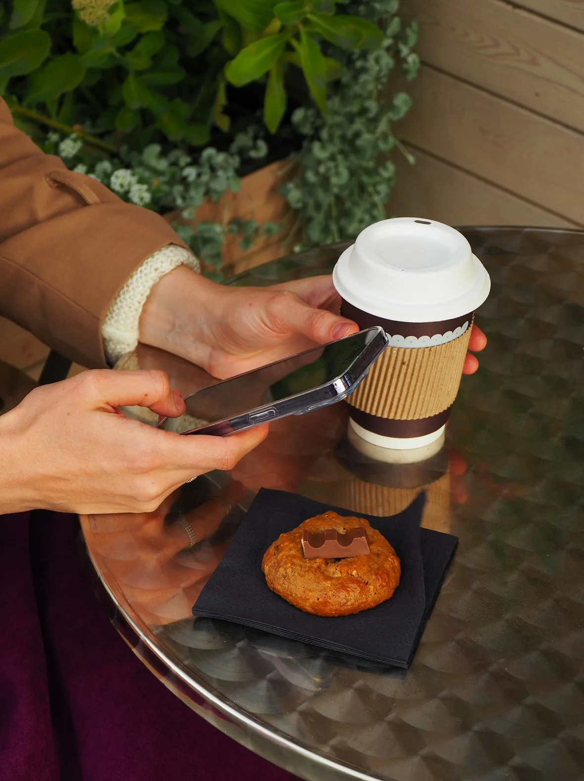 Coffee cup and pastry on a cafe table beside a phone
