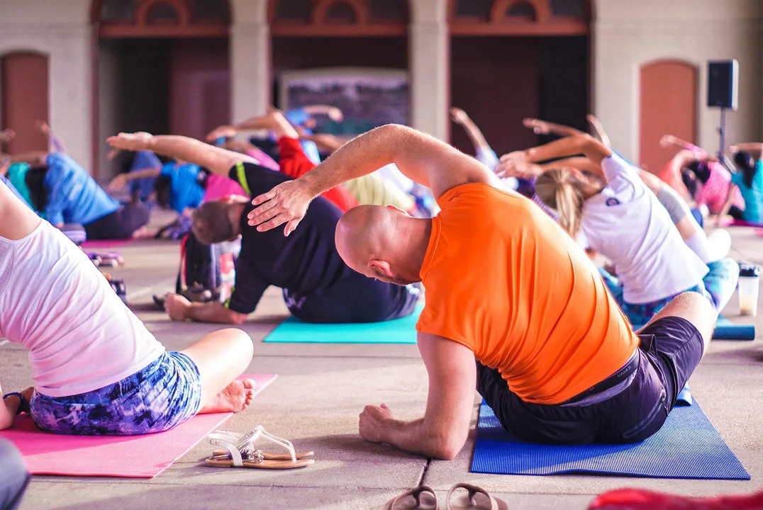 Group yoga class stretching on mats in a fitness studio