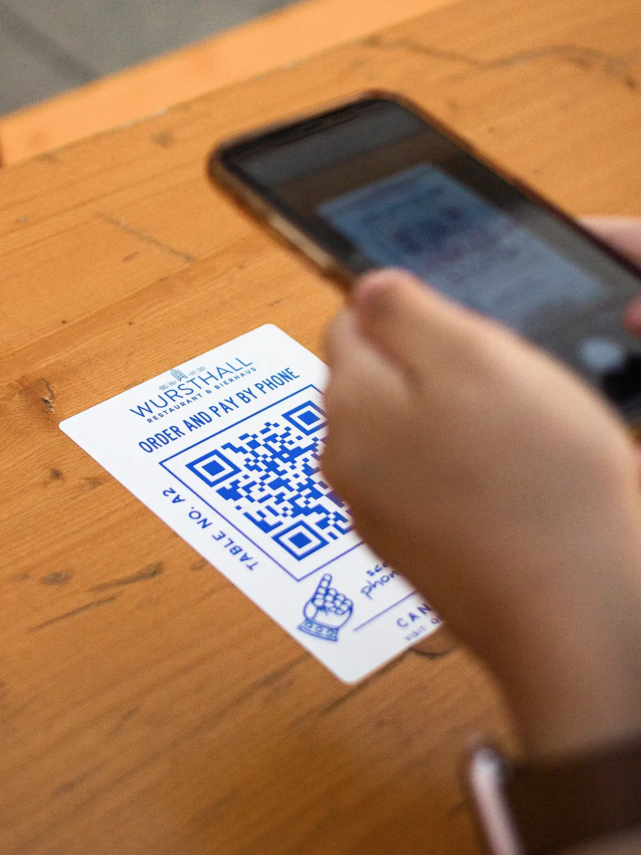 Person scanning a restaurant table tent QR code with a phone to join an SMS list