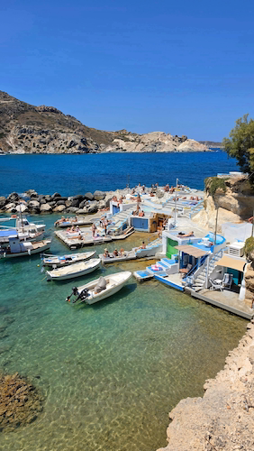 Mediterranean fishing harbour with boats, rocky coastline and seaside terraces