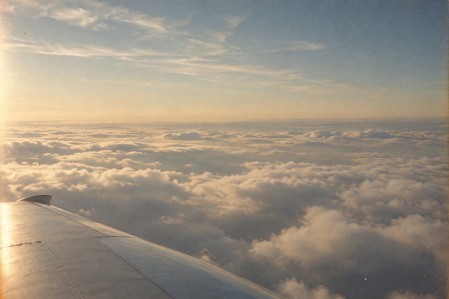 Airplane wing above a sea of clouds at sunrise