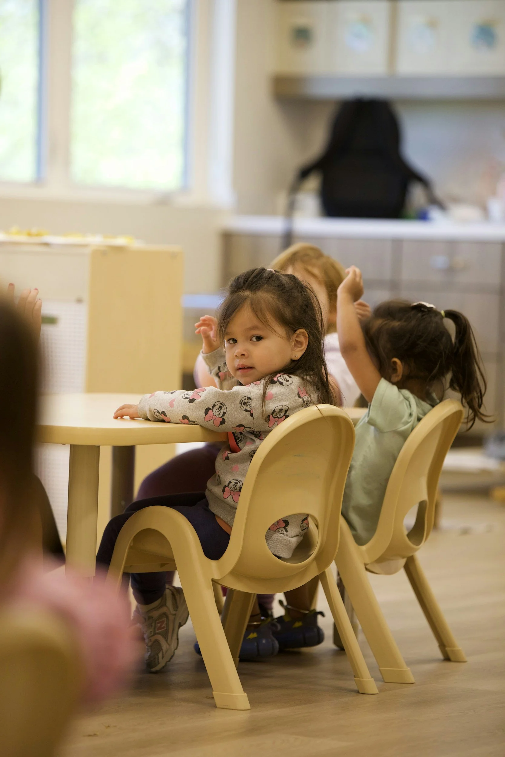 Quiet young child sitting alone at a classroom desk during a lesson