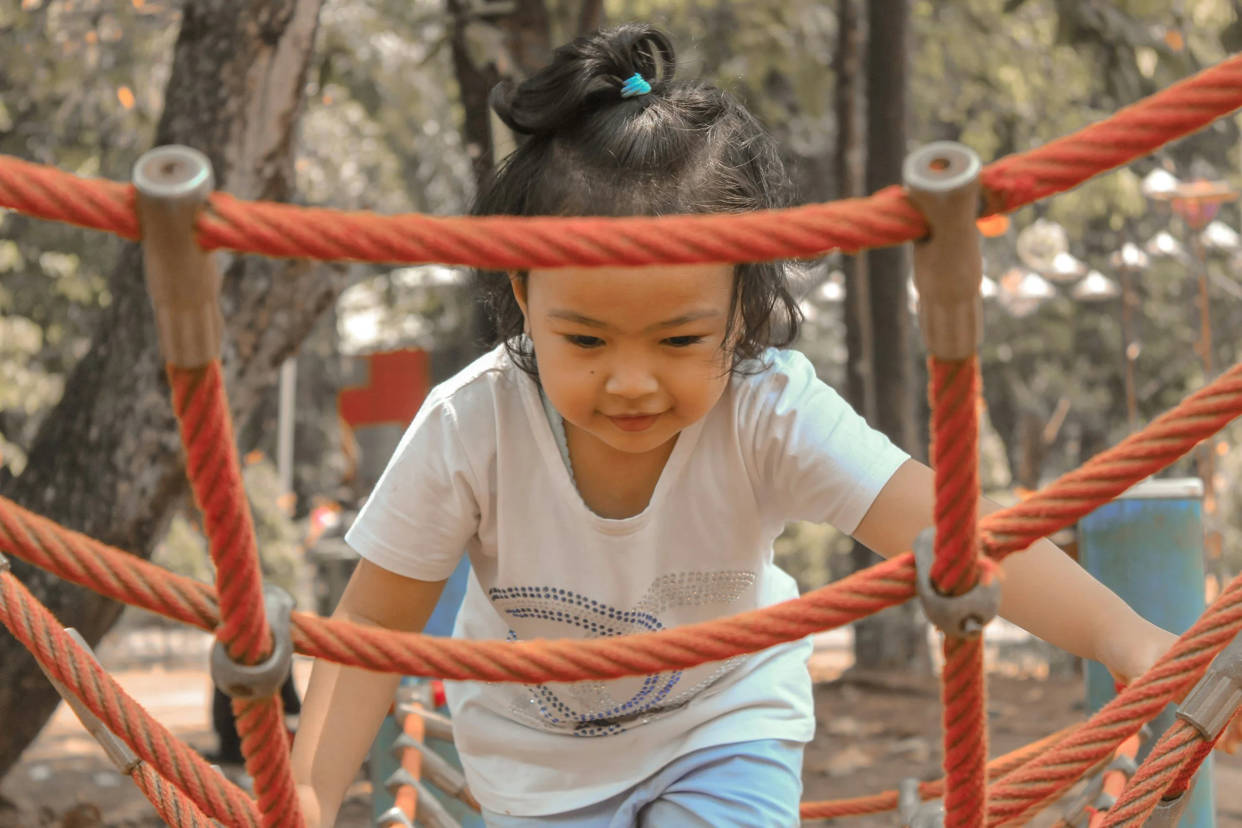 Young child carefully balancing while climbing on outdoor playground equipment