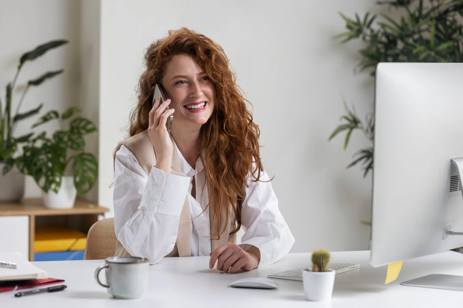 Medewerker neemt lachend een klantgesprek aan aan haar bureau
