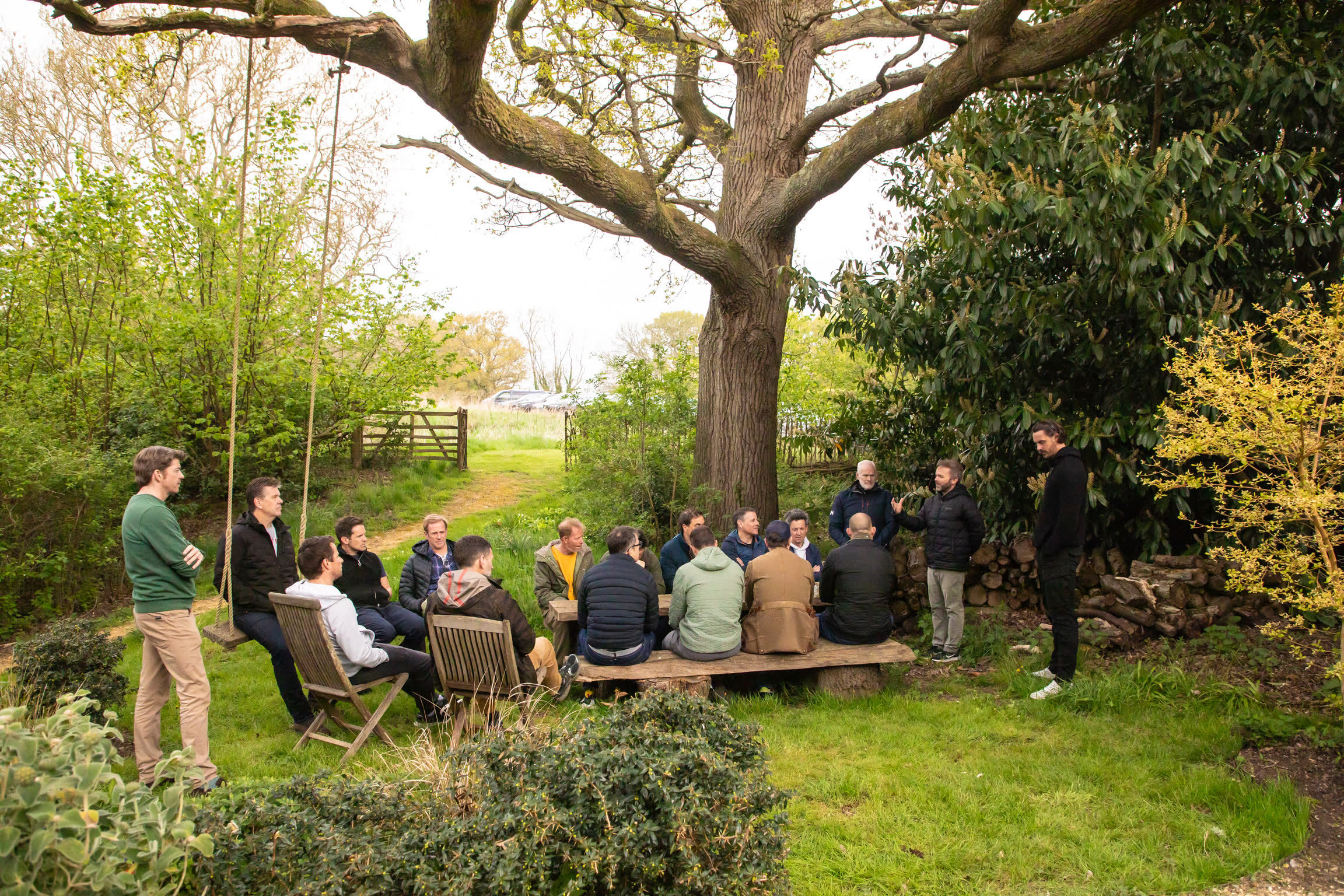 Monumental members sitting in a circle beneath an oak at a Monksmead retreat