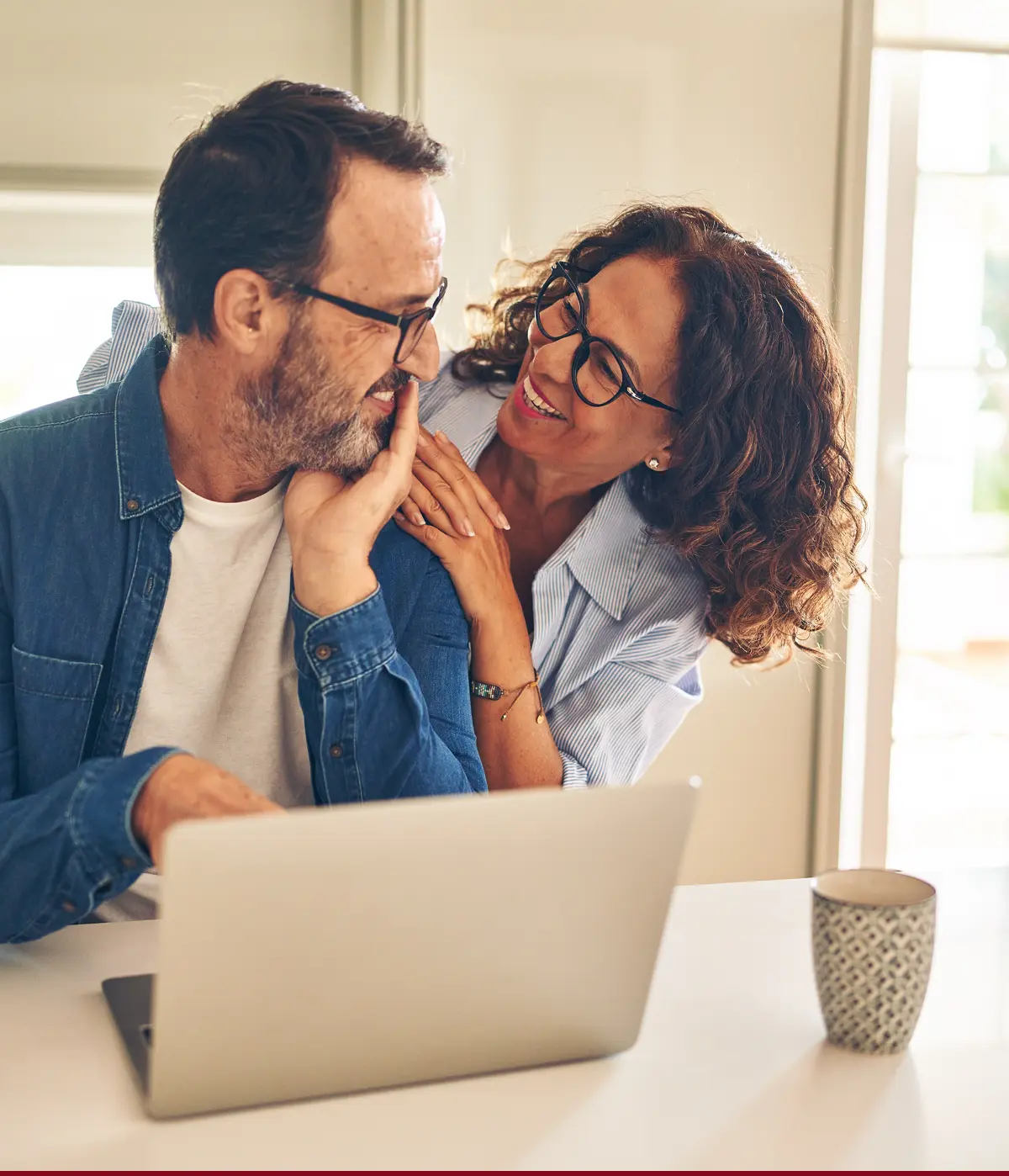 Middle-aged couple smiling at each other while looking at a computer