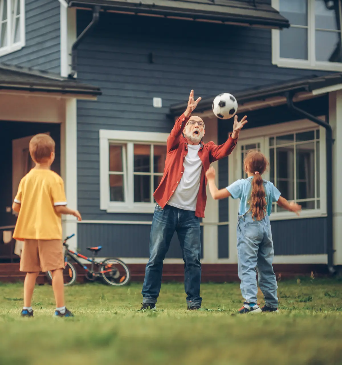 Grandfather playing soccer with grandkids outside