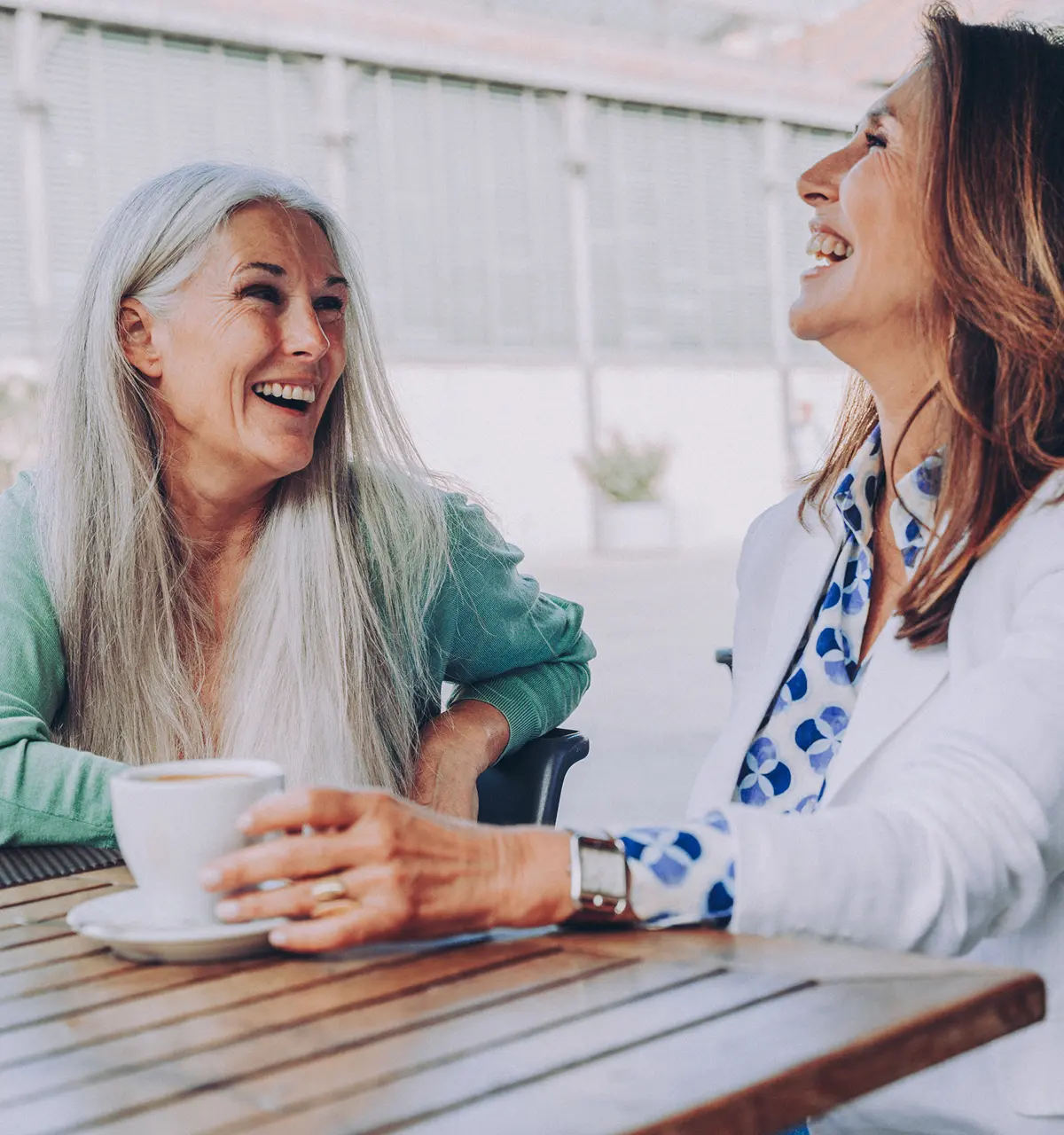 Middle-aged women friends having coffee and laughing