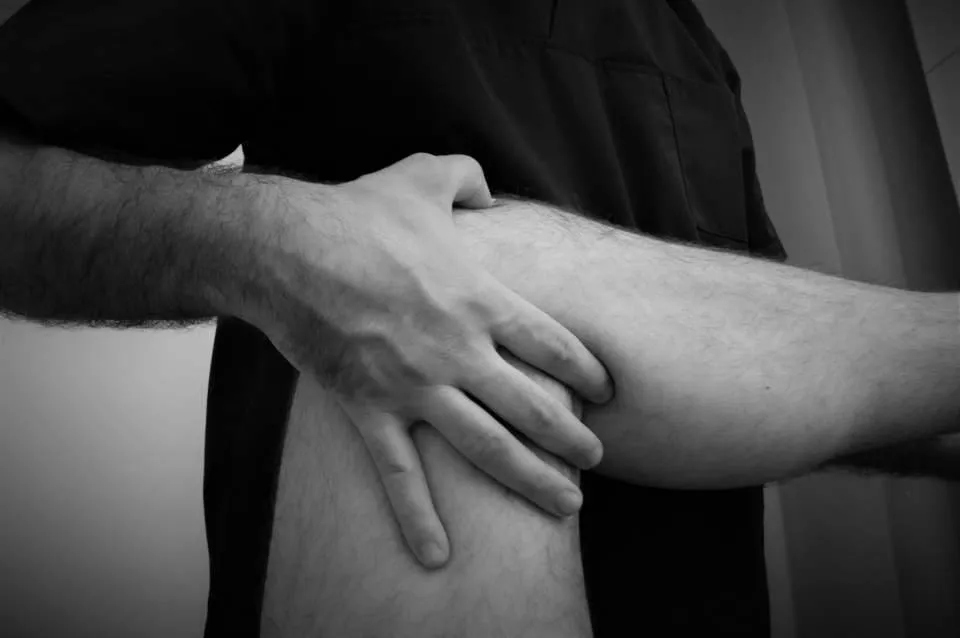 Mains du praticien en manipulation sur un genou, photo en noir et blanc
