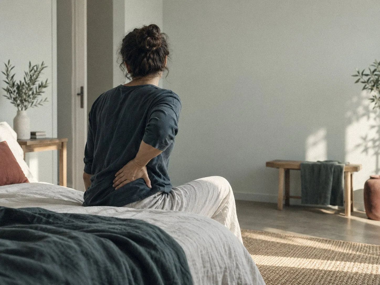 Douleur lombaire chez l'adulte : personne assise au bord d'un lit, main dans le bas du dos