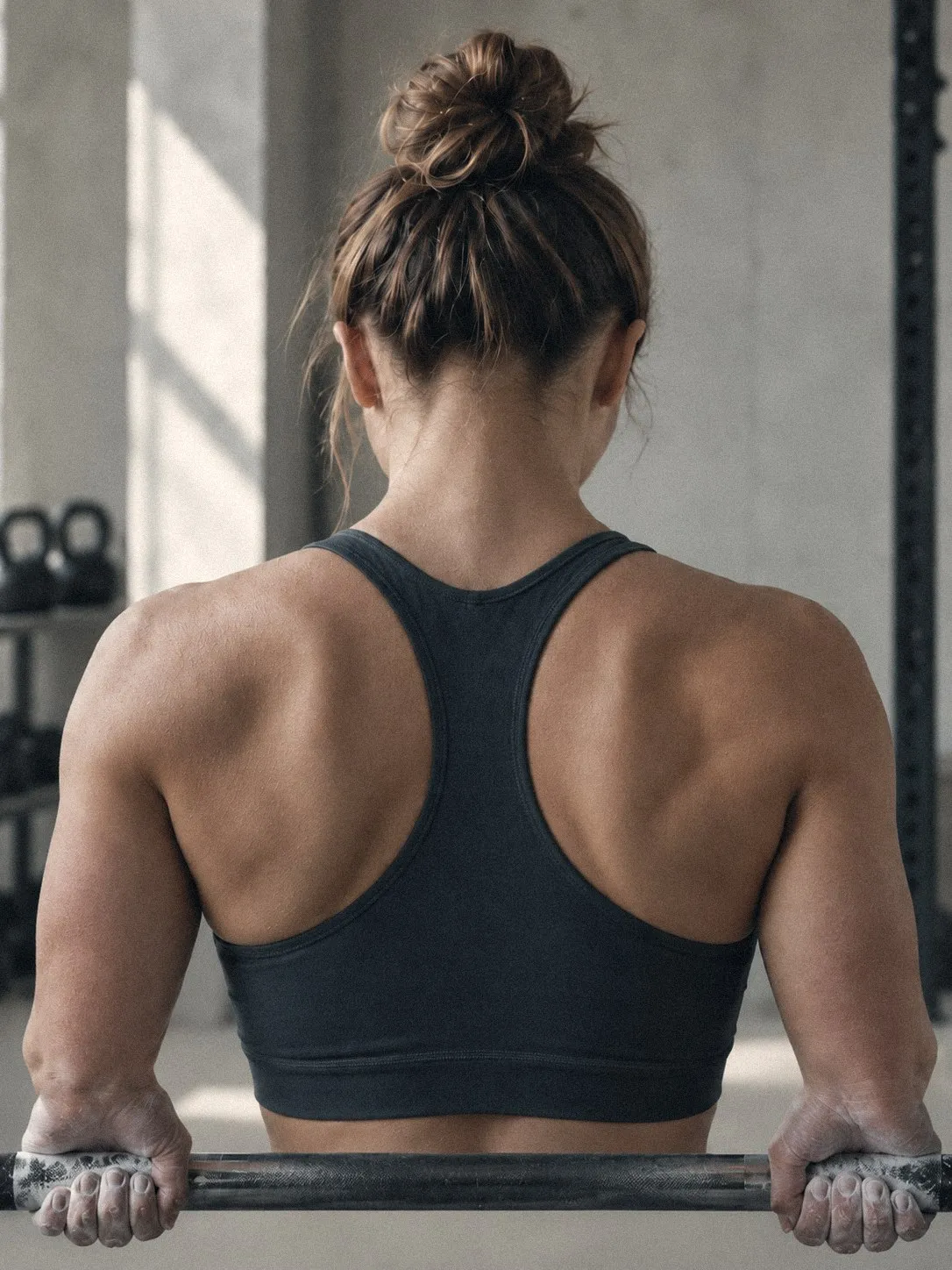 Sportive de dos en salle de musculation, mains sur la barre